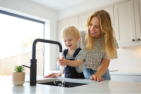 L’enfant se lave les mains dans la cuisine pendant que sa mère le regarde